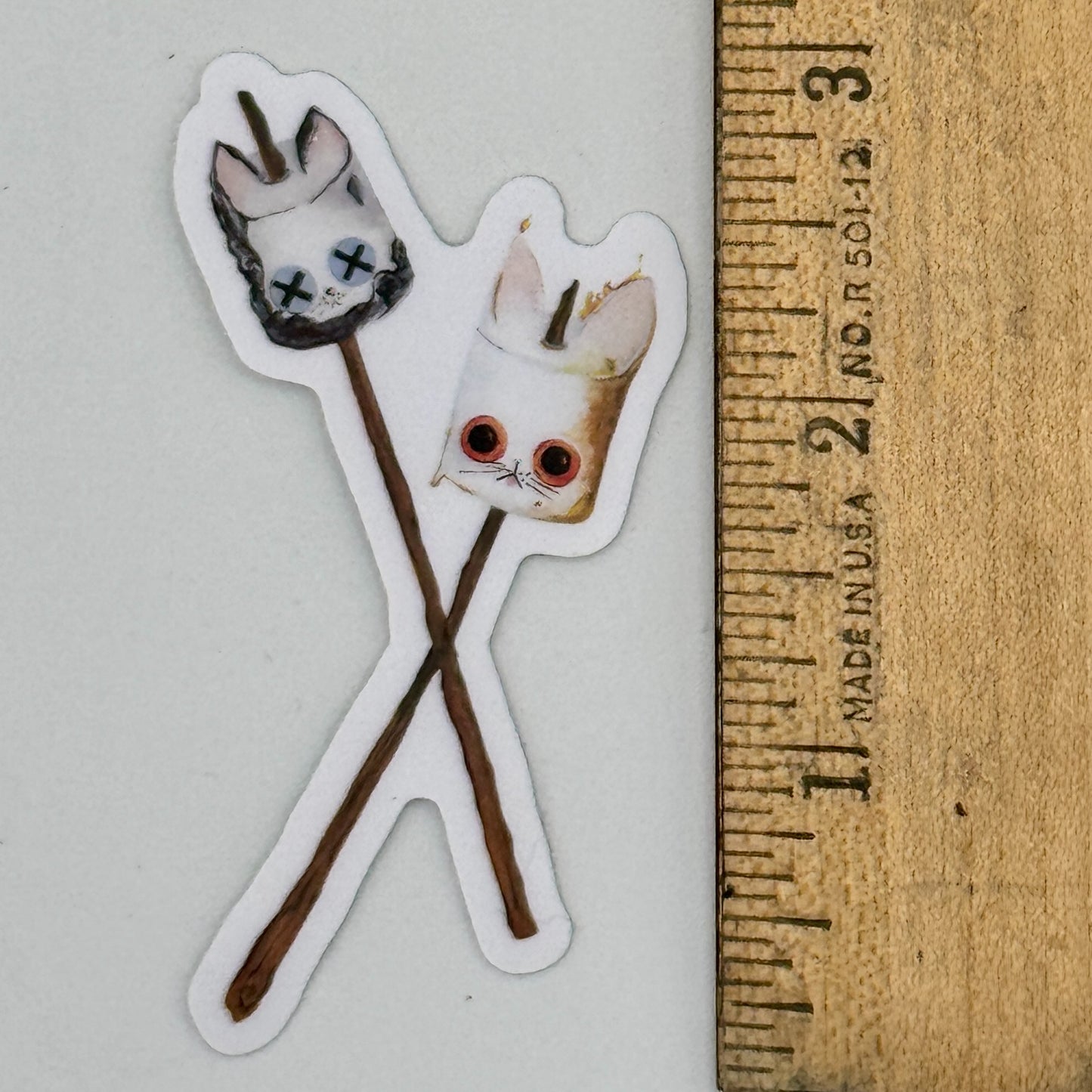 Sticker of a the Roasted and Toasted KittenMallow next to a ruler for scale